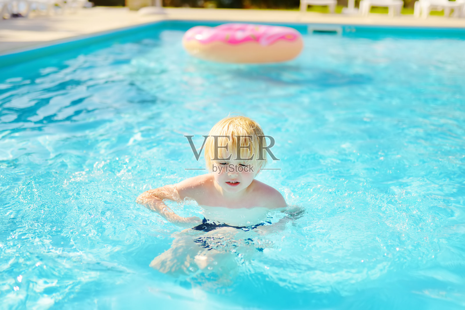 在希腊，一个小男孩在假期和家人在游泳池里游泳照片摄影图片
