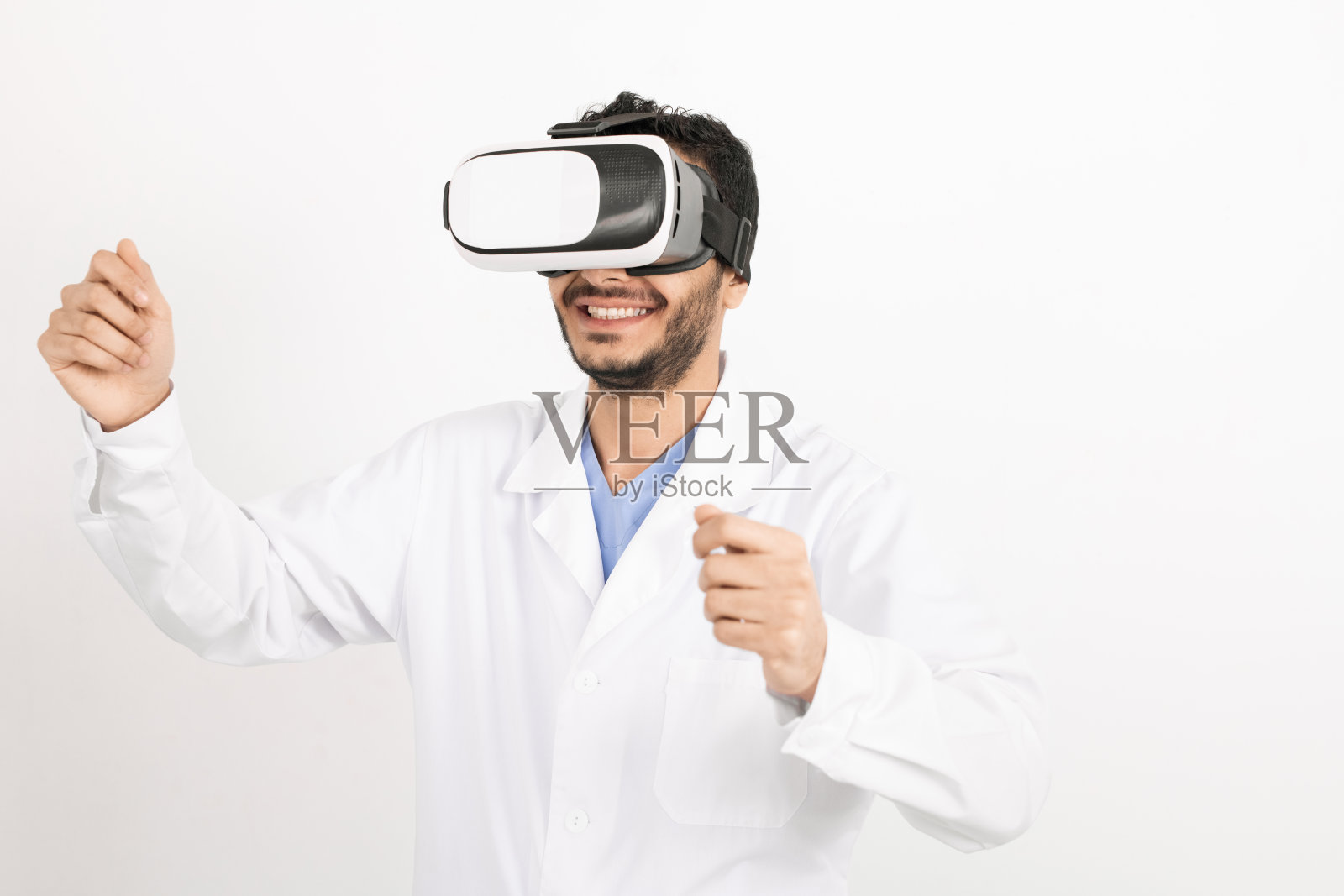 年轻微笑的男医生身穿白大褂，戴着vr头盔，孤立地站着照片摄影图片