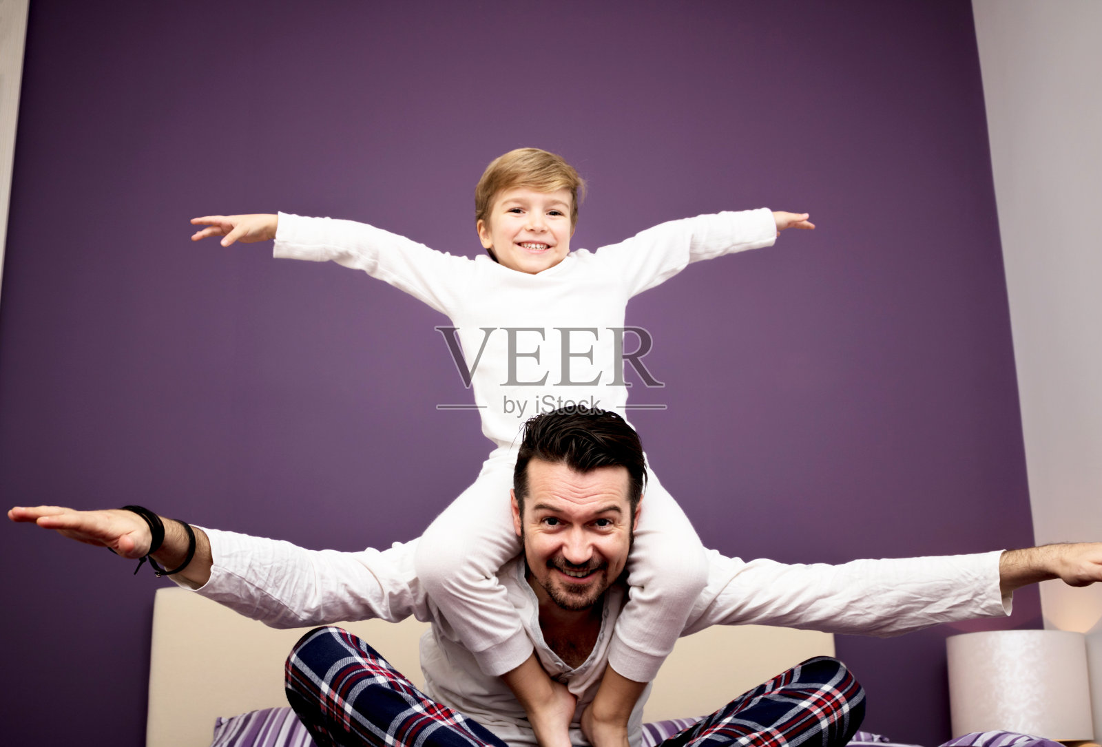 下图是卧室里玩耍的父亲和儿子。照片摄影图片