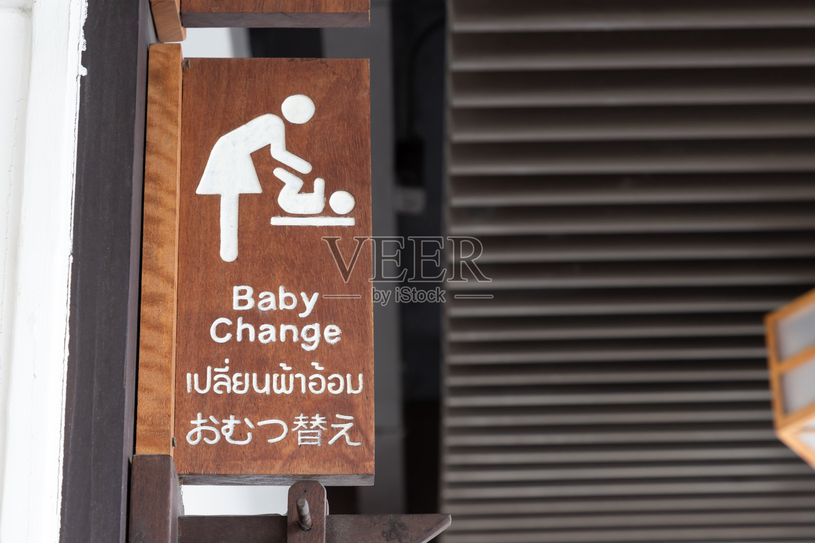 婴儿更换标志使用三种语言，英语，泰语和日本的措辞。更换婴儿的木制标志。照片摄影图片