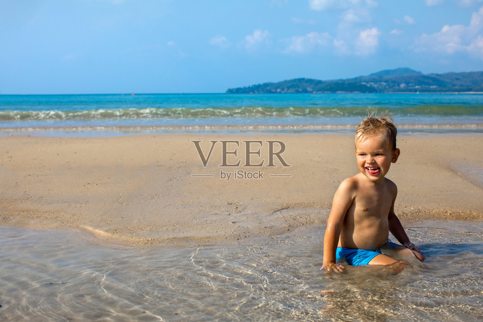 夏天，快乐的孩子坐在海边的水里照片摄影图片