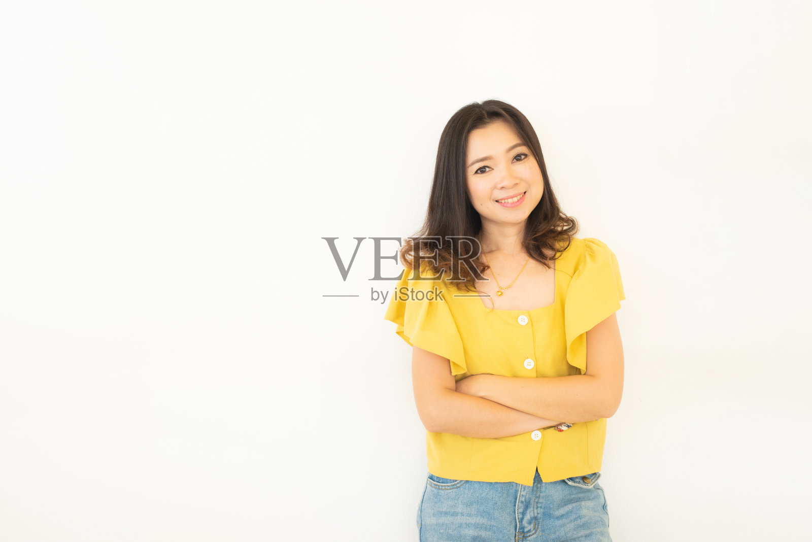 肖像的成功商业亚洲妇女在黄色连衣裙与双臂交叉和微笑孤立在白色的背景，年轻的商业妇女微笑，看着相机，快乐的感觉概念。照片摄影图片