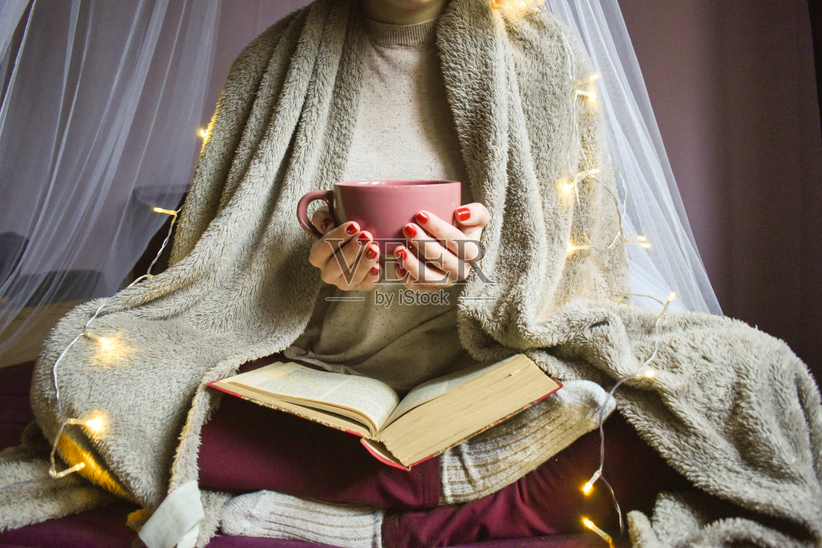 一个女人在床上看书，手里拿着一个咖啡杯照片摄影图片