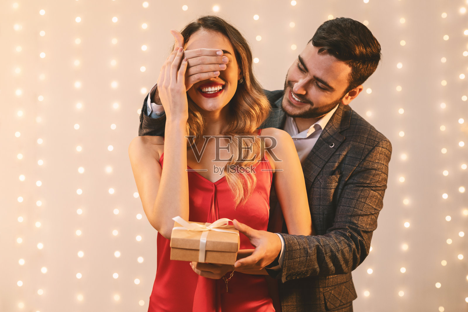 优雅的男人遮住女友的眼睛，给她礼盒照片摄影图片