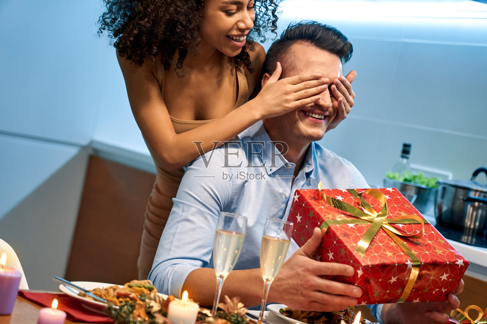 两个年轻人吃着浪漫的晚餐，互赠礼物照片摄影图片