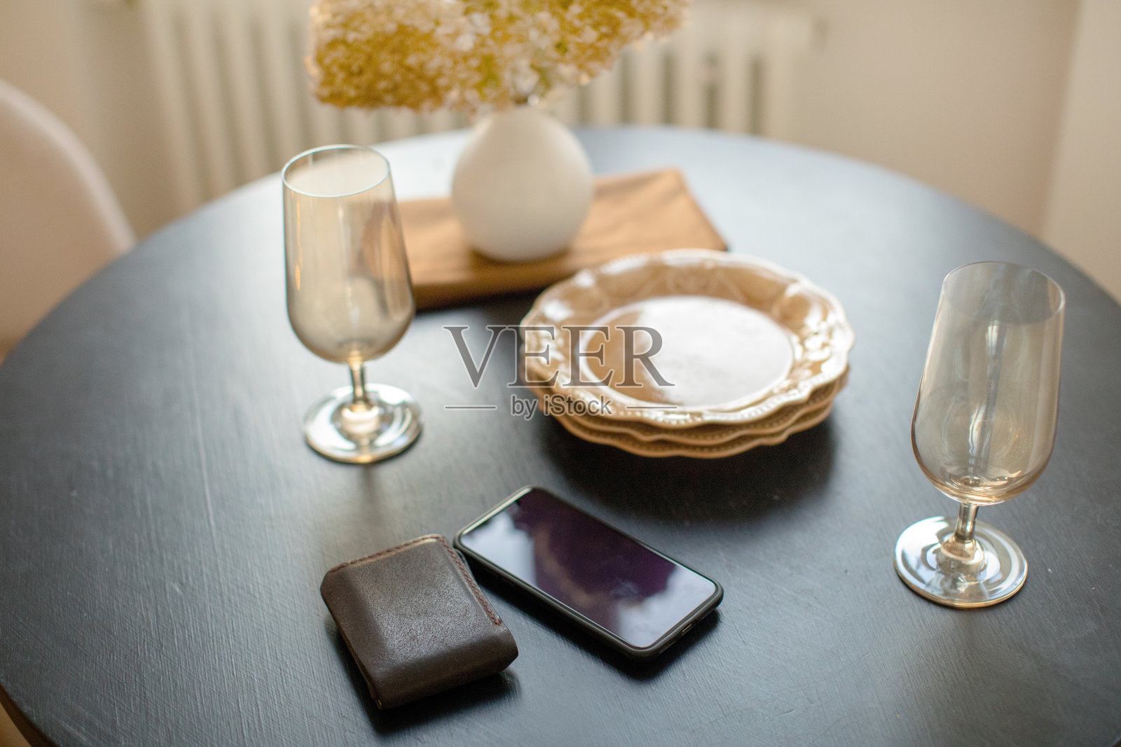 餐具、智能手机和钱包放在摆着花瓶的桌子上照片摄影图片