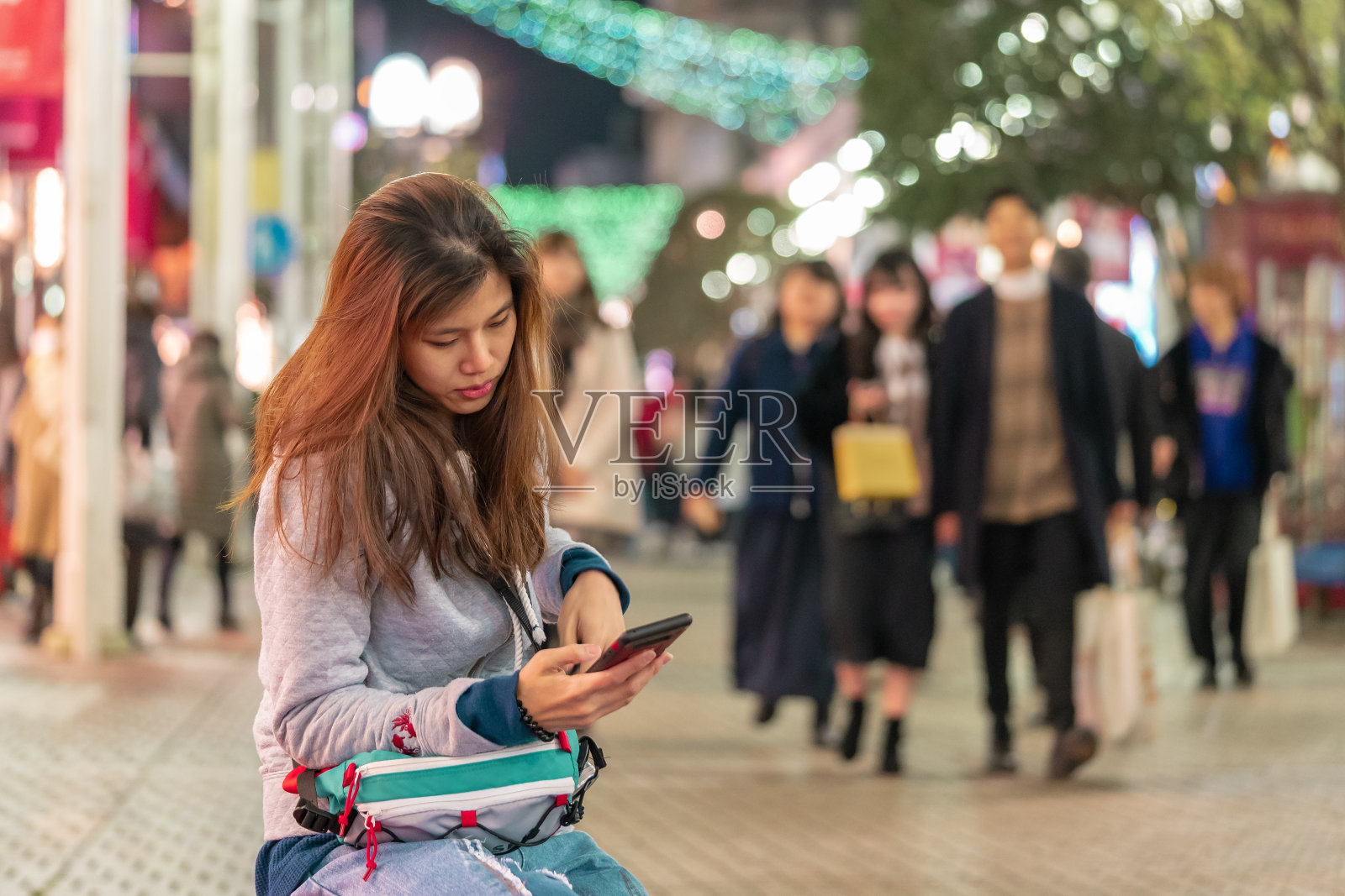 孤独的日本女孩正在给一个在购物街上见面的人发短信照片摄影图片
