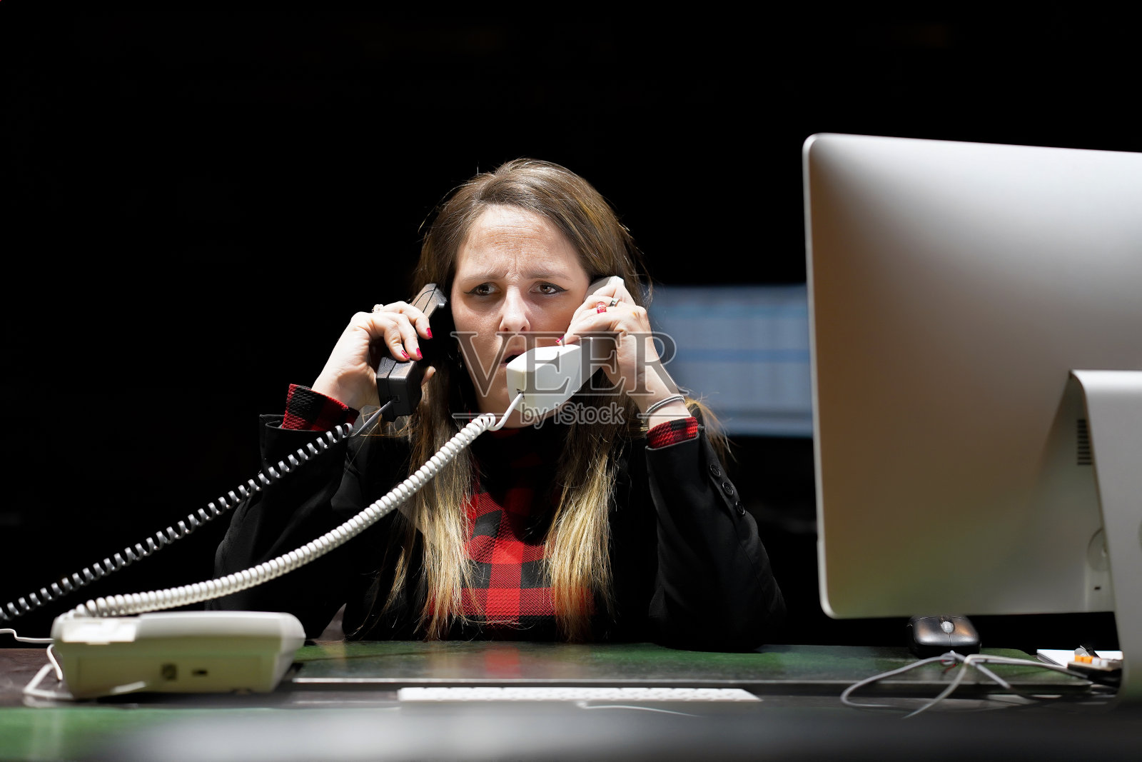 一个女人坐在办公桌前接电话。照片摄影图片