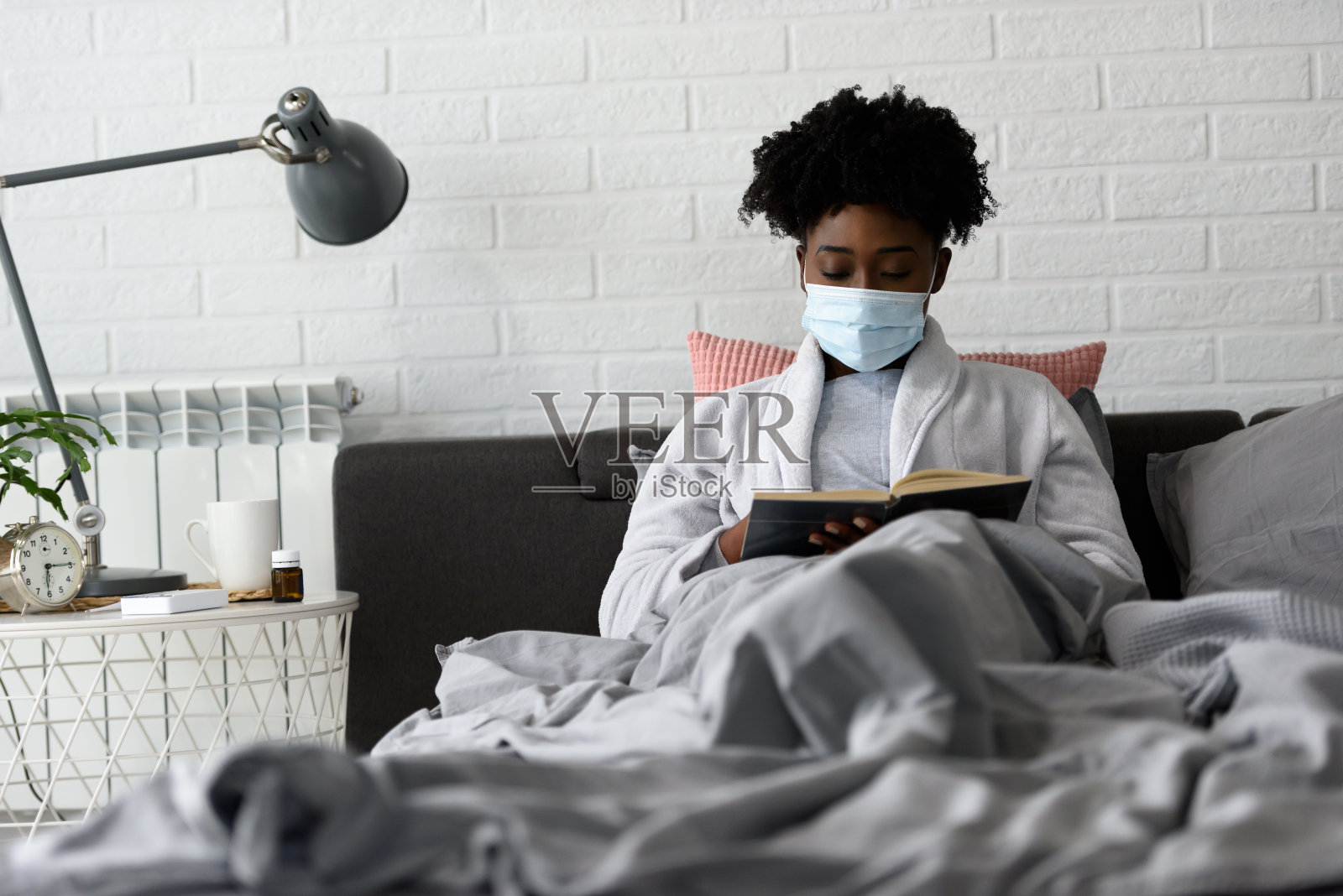 年轻的非裔美国妇女躺在家里的床上。得了流感，生病了。照片摄影图片