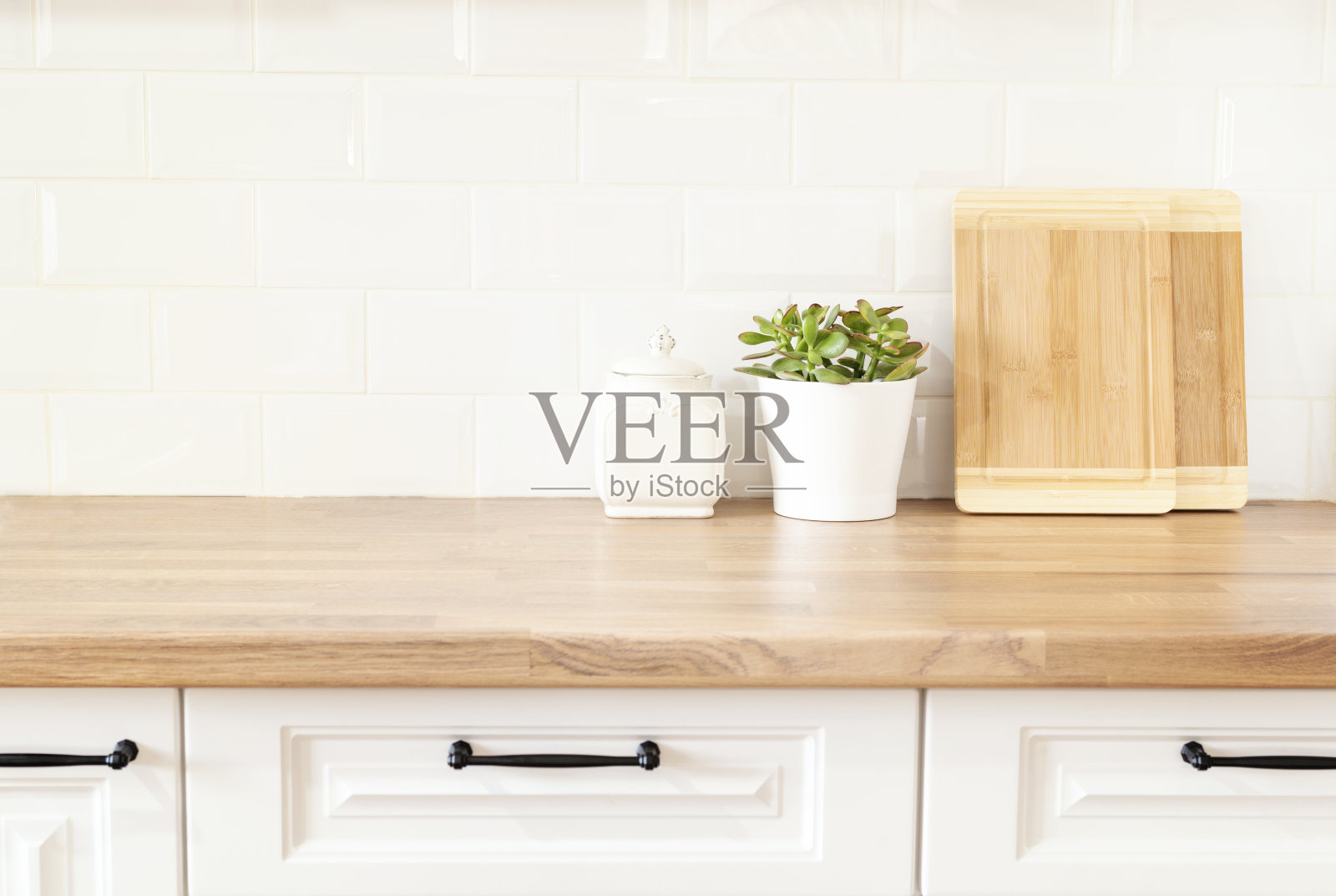 明亮和干净的厨房与白色橱柜，靠近。切菜板，木质操作台上的绿色多汁锅。现代厨房室内厨具。白色瓷砖背景照片摄影图片