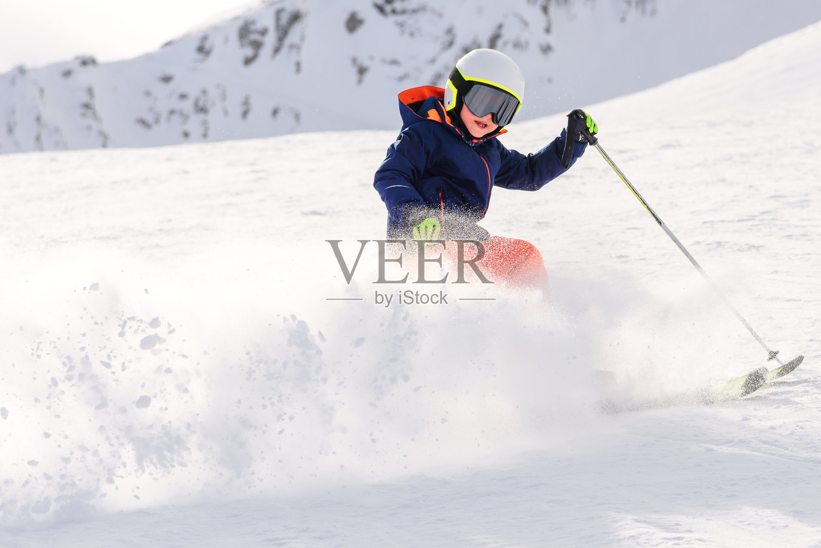 孩子们在山上滑雪。儿童滑雪比赛。滑雪突然停住，扬起一大片雪尘。照片摄影图片