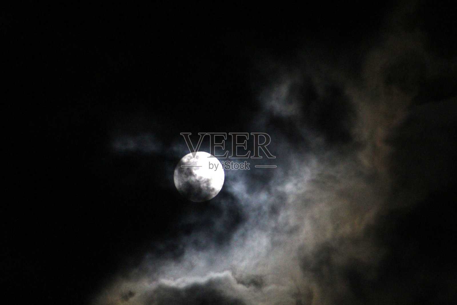 在黑暗的天空中，满月在白云之上照片摄影图片