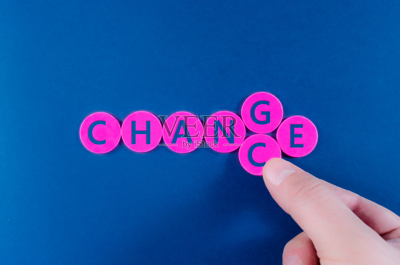 一个商人的手在改变字母G和C，把一个Change标志变成了拼写在粉色圆圈上的Chance。照片摄影图片