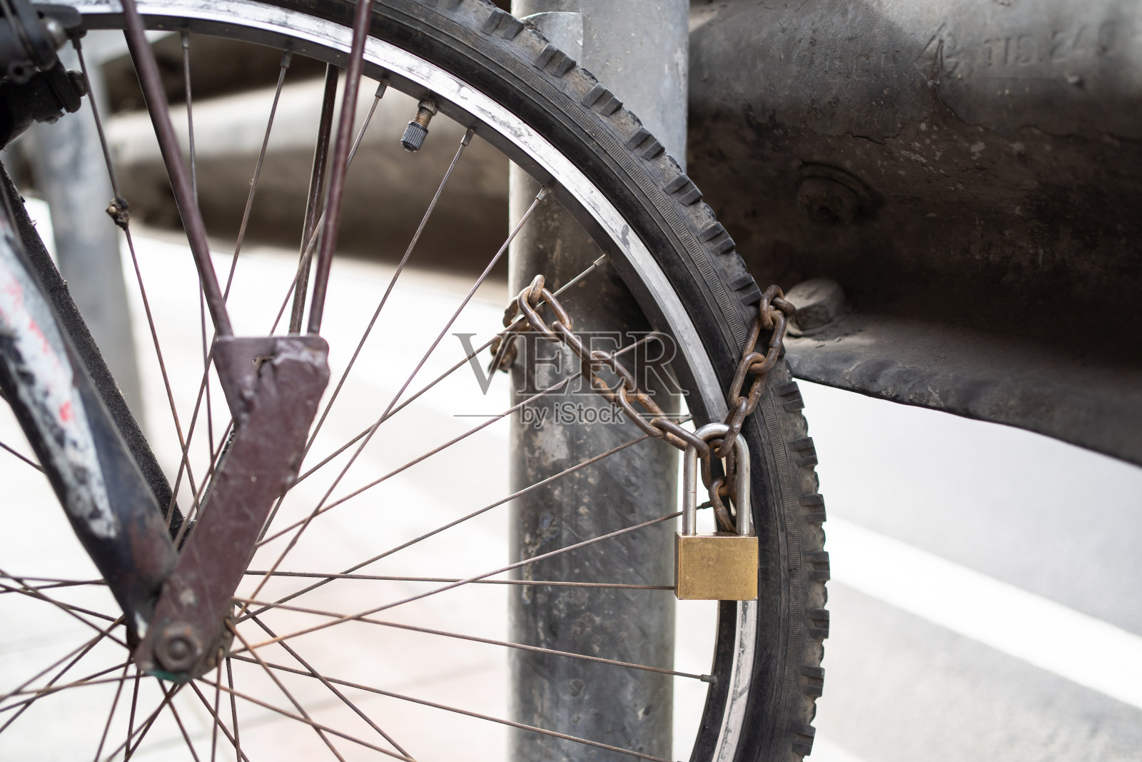 用链条和杆子将自行车锁在人行道上照片摄影图片
