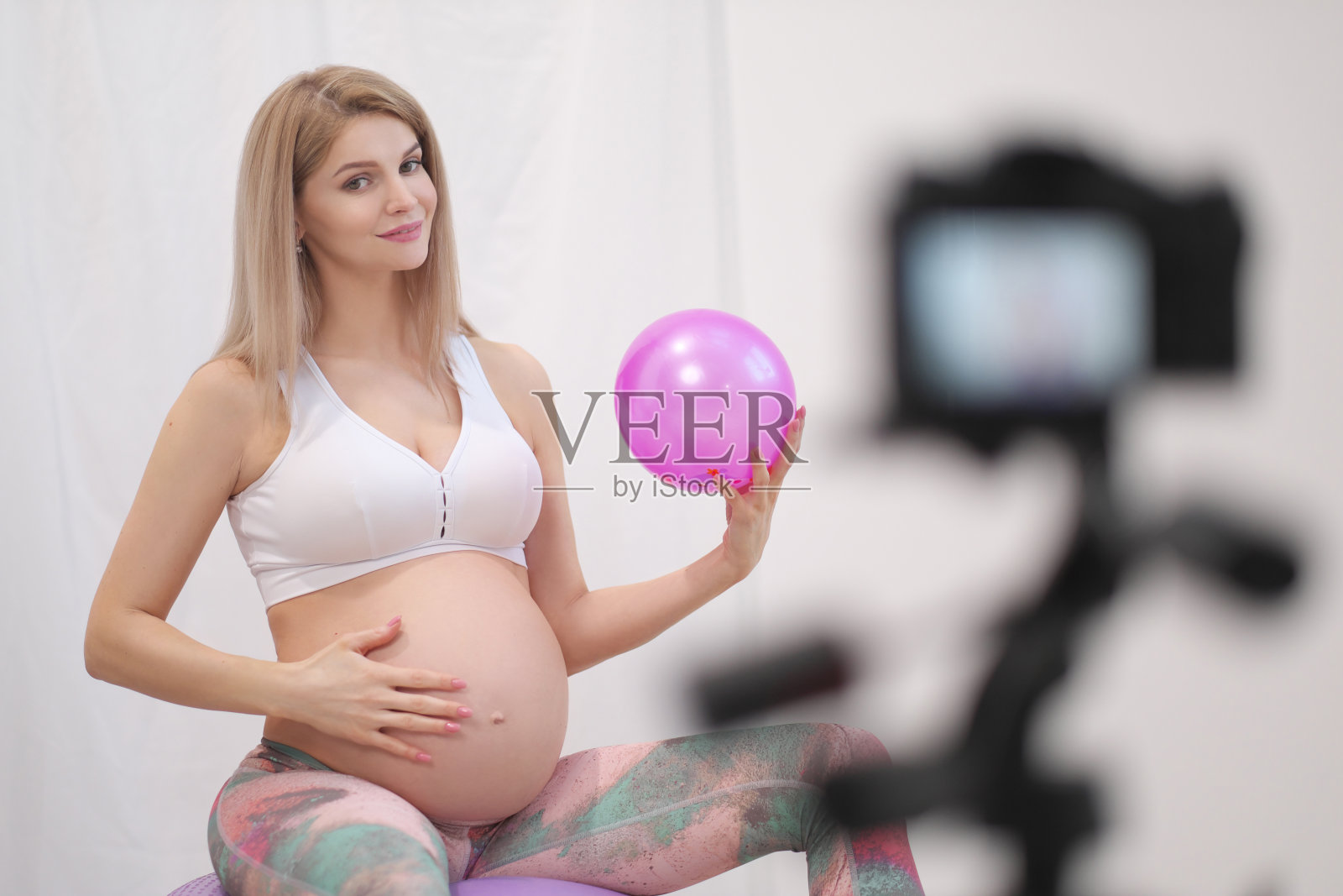 一位年轻的孕妇在博客中谈论球类运动。照片摄影图片