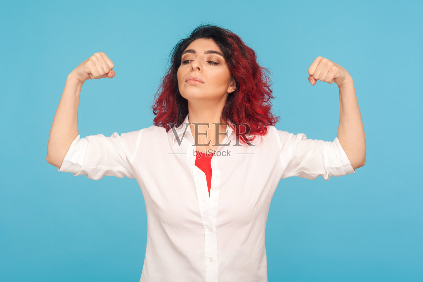 我有力量!这是一幅骄傲的红发女子的肖像，她举起双手展示肱二头肌，感觉自己很有力量照片摄影图片