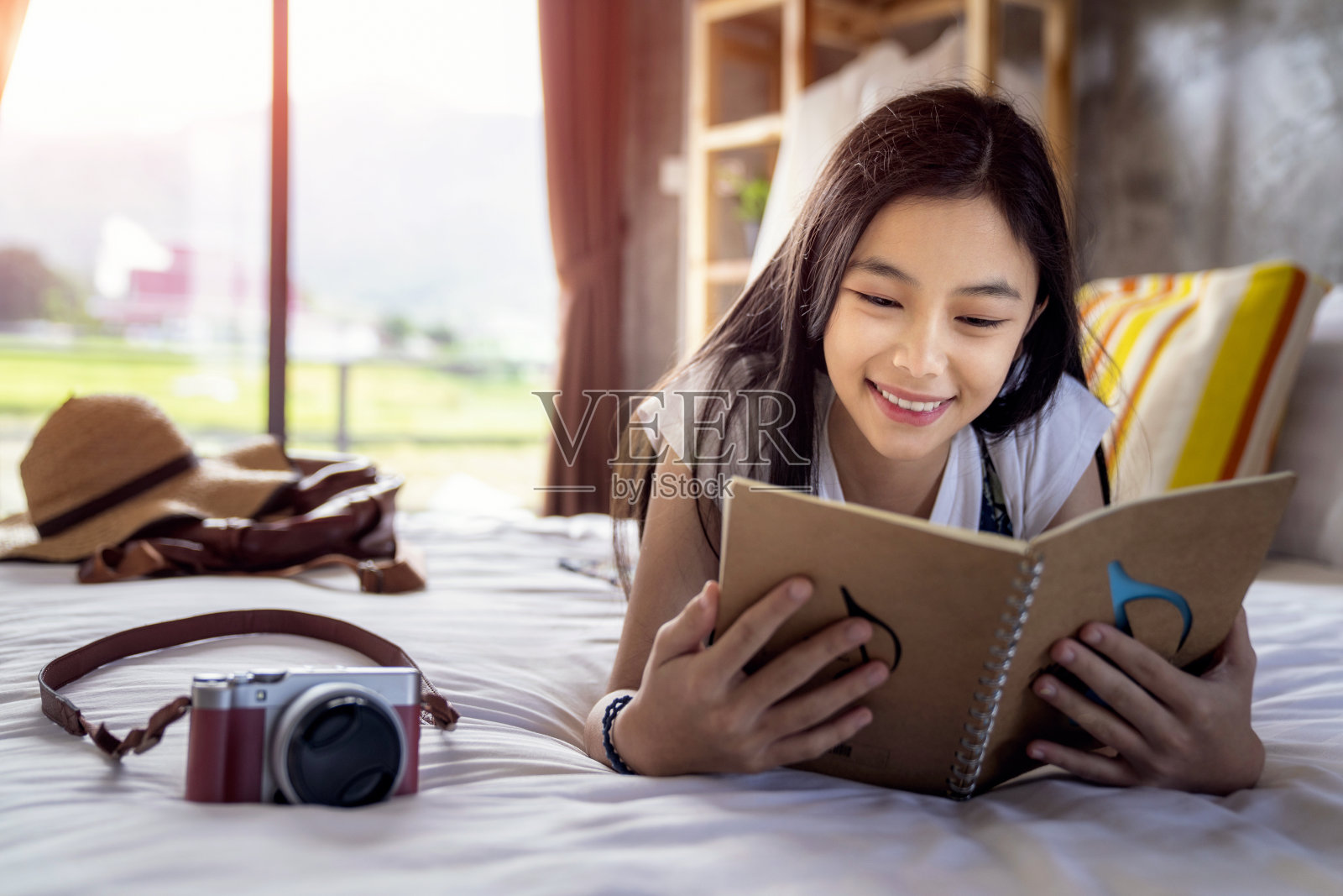 一个亚洲女孩在床上读了一本旅行笔记照片摄影图片