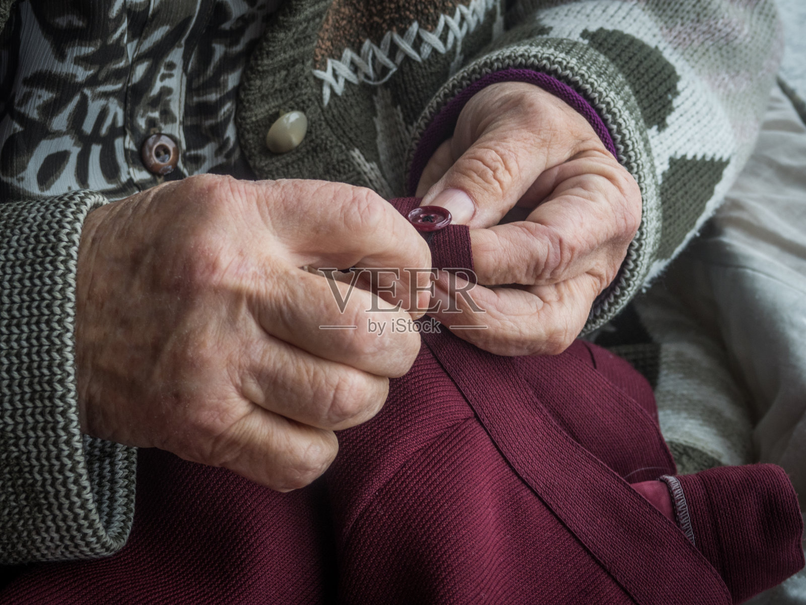 老妇人的手在缝纽扣照片摄影图片