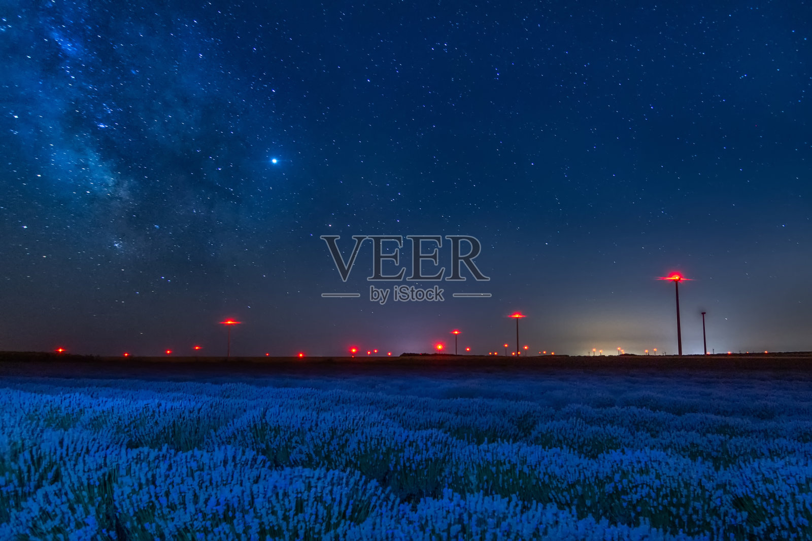美丽的星空与银河和蓝天之上的薰衣草和红色的风力涡轮机的灯光照片摄影图片