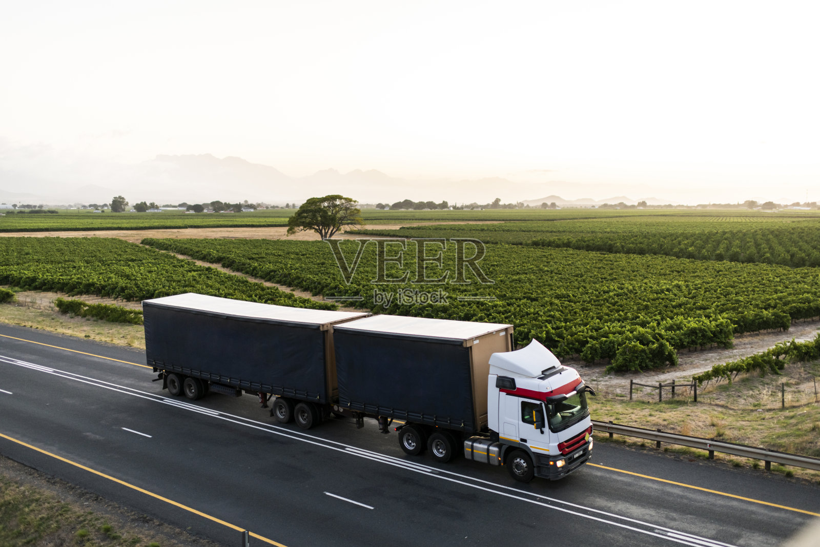 卡车在日出时行驶在高速公路上，穿过碧绿的南非风景照片摄影图片