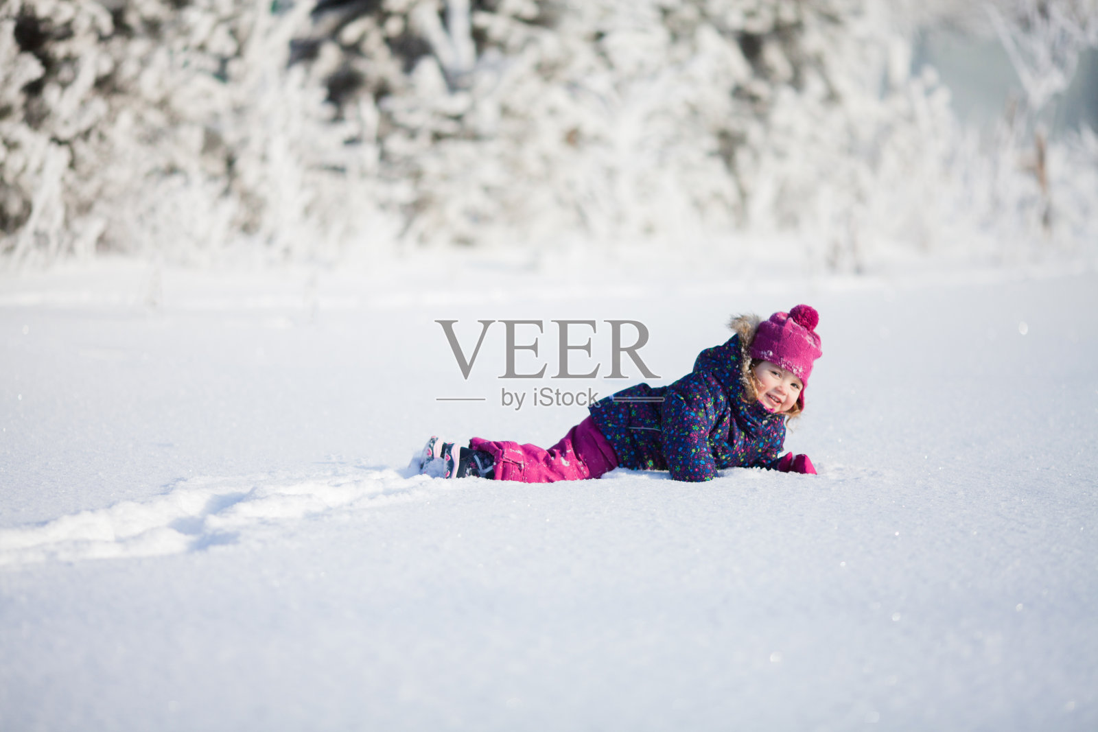 一个可爱的蹒跚学步的小女孩在一个阳光明媚的冬日户外。照片摄影图片
