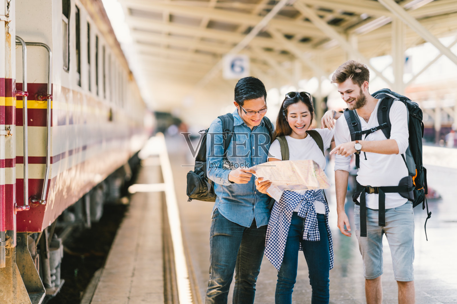 多民族群体的朋友，背包旅行者，或大学生使用通用的当地地图导航一起在火车站站台。亚洲旅游活动或铁路旅行的旅游概念照片摄影图片
