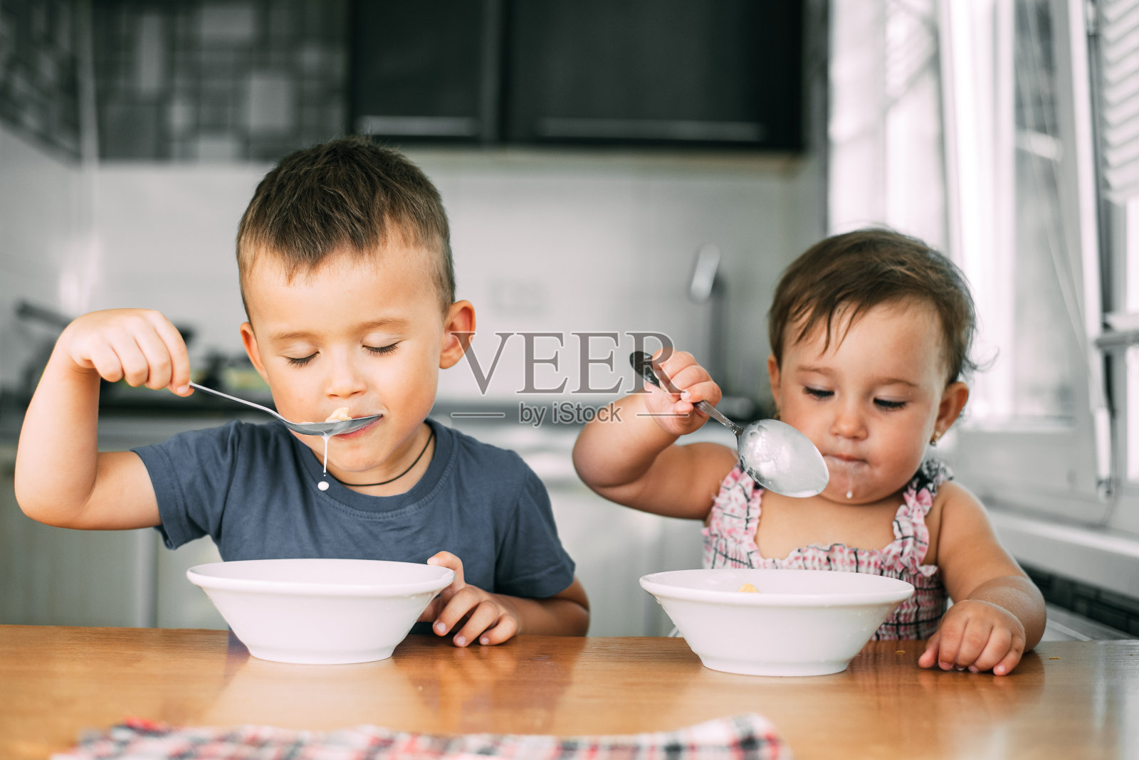 哥哥和妹妹白天在厨房里喝牛奶吃玉米片，非常有趣和可爱，肮脏和有趣照片摄影图片