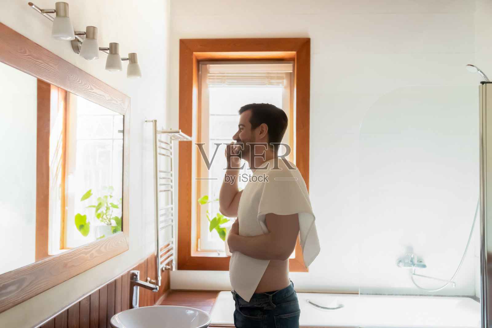 年轻的白人男人在现代浴室刷牙照片摄影图片