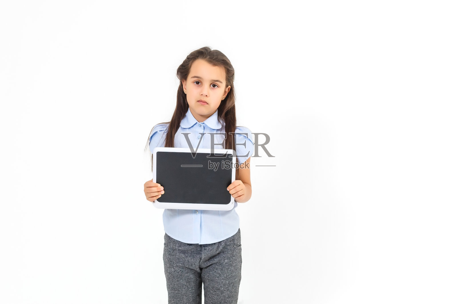 漂亮的女学生穿着商务套装，手里拿着平板电脑，看着摄像头，选择性地聚焦在平板电脑上照片摄影图片