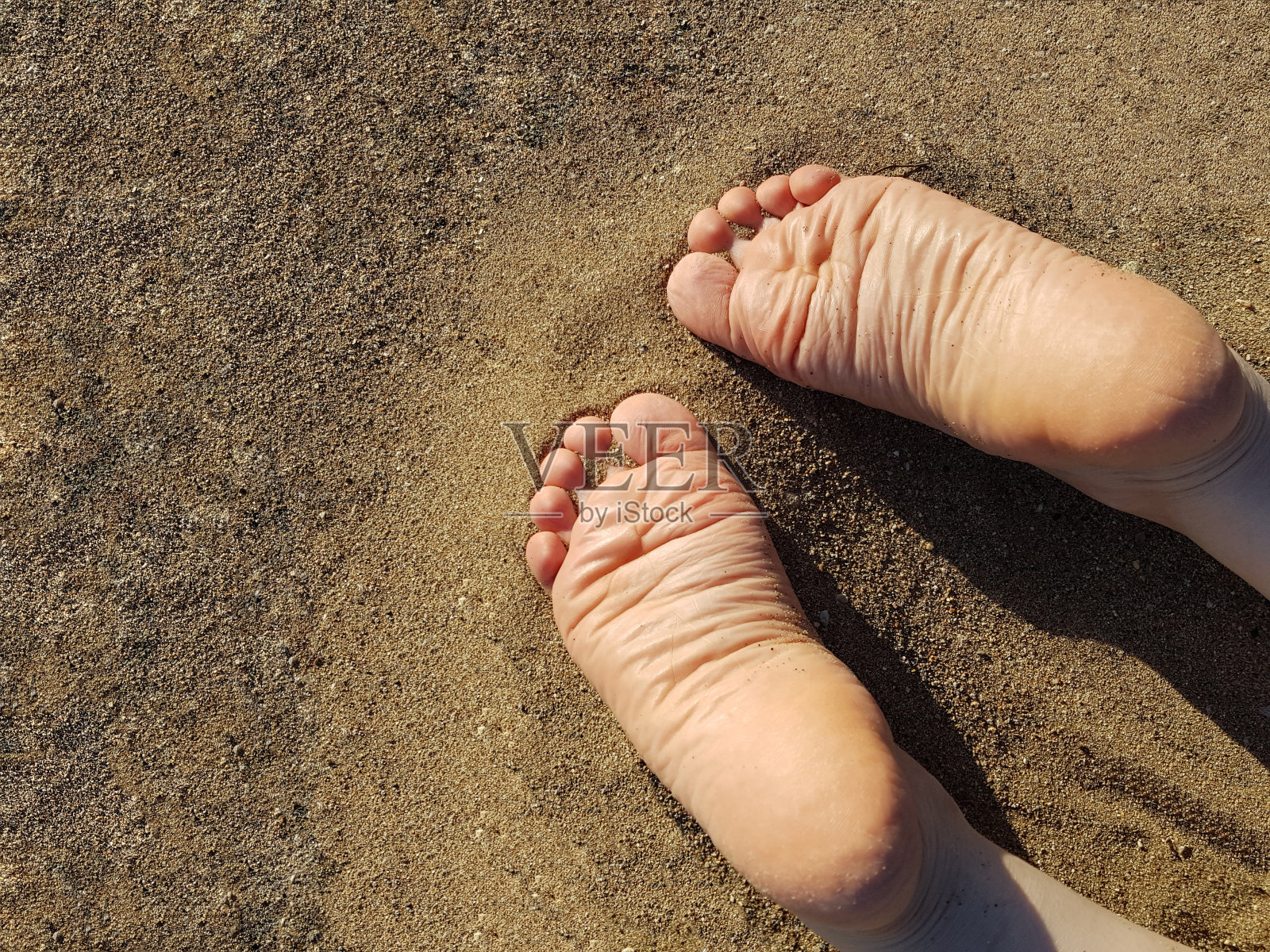 一个女人的脚面朝下躺在沙滩上照片摄影图片
