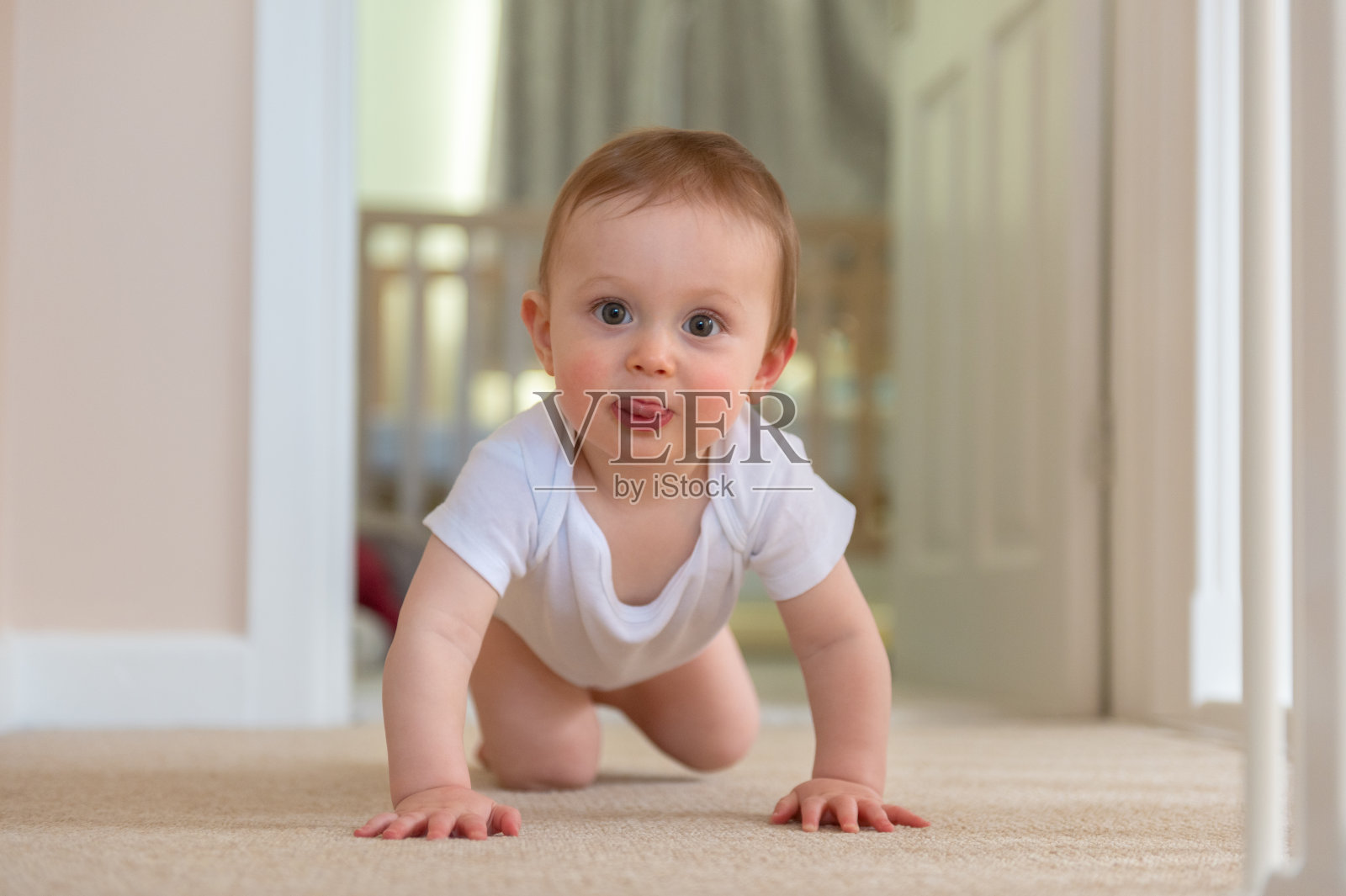 9个月大的小男孩在地板上爬照片摄影图片