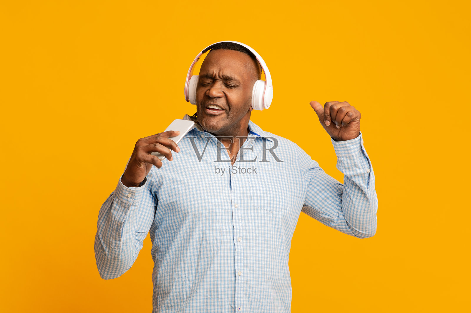 感情丰富的非洲成熟男人戴着耳机在电话里唱歌照片摄影图片