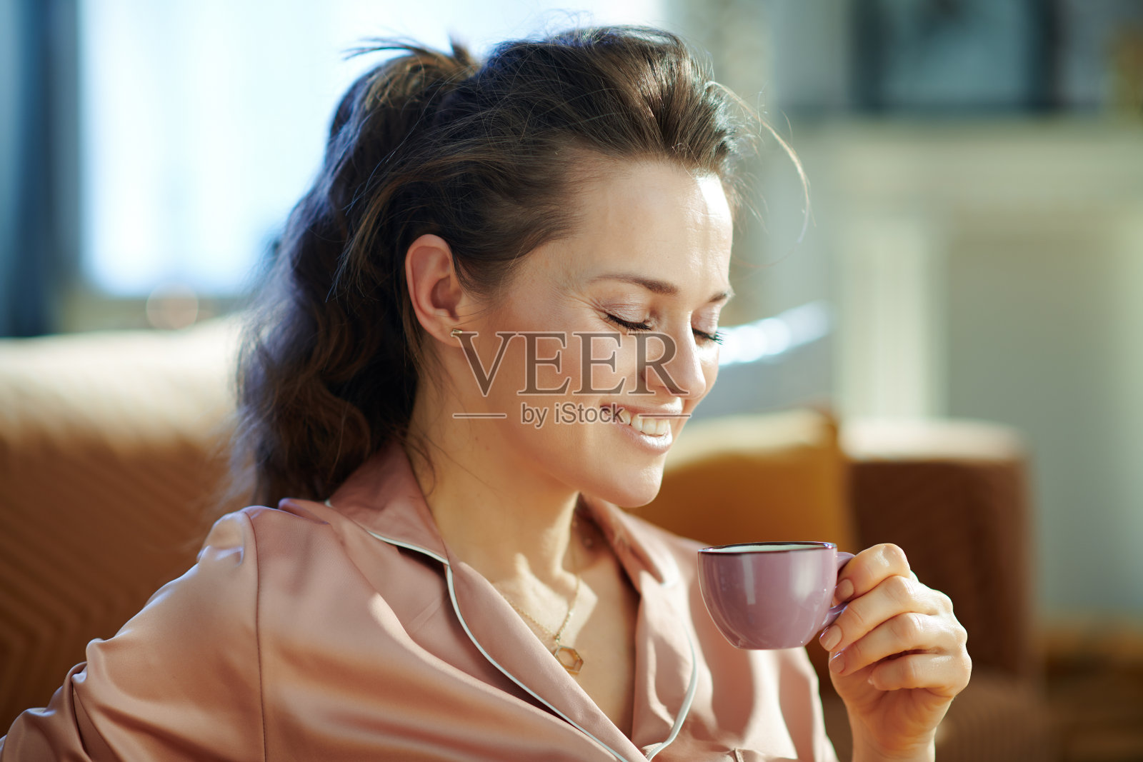女人在阳光明媚的冬日里在现代客厅里喝着咖啡照片摄影图片