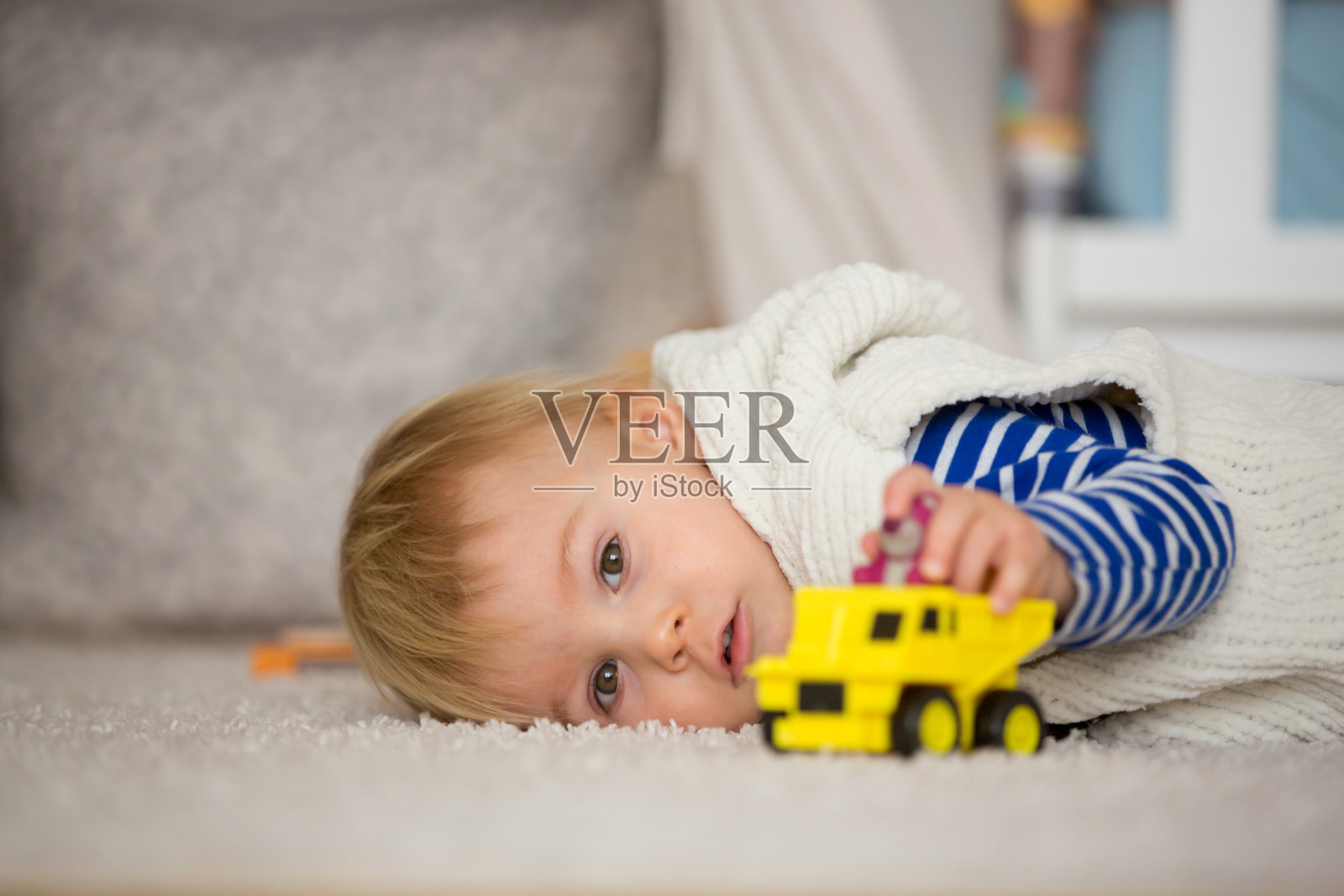 可爱的蹒跚学步的男孩，在家里的儿童房玩汽车玩具，儿童幸福的概念照片摄影图片