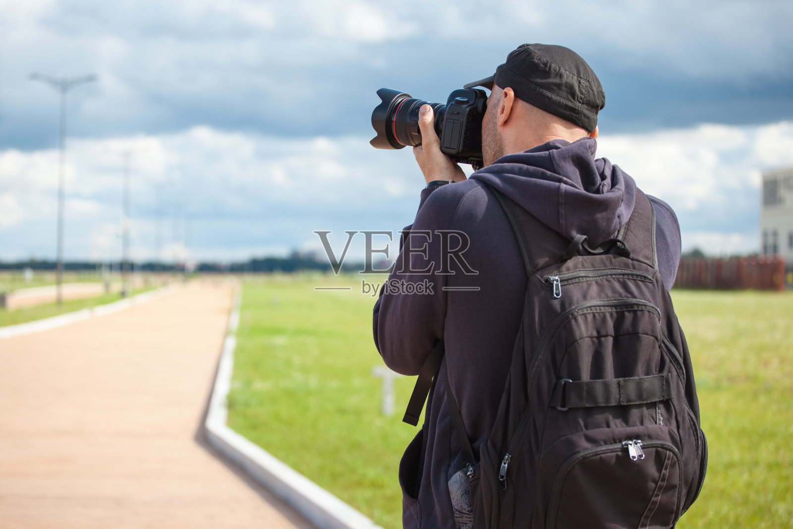 男性摄影师用一个大的专业相机看着取景器拍摄照片照片摄影图片