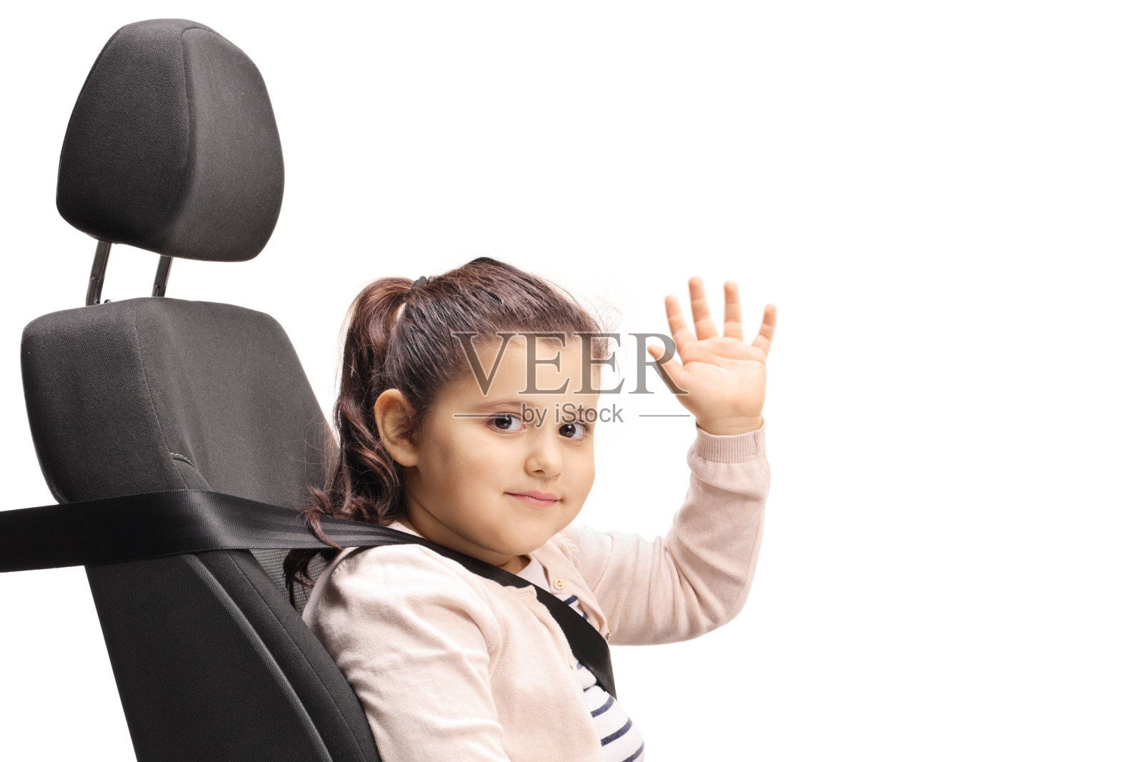 女孩坐在汽车座椅上，系着安全带，看着镜头，挥着手照片摄影图片