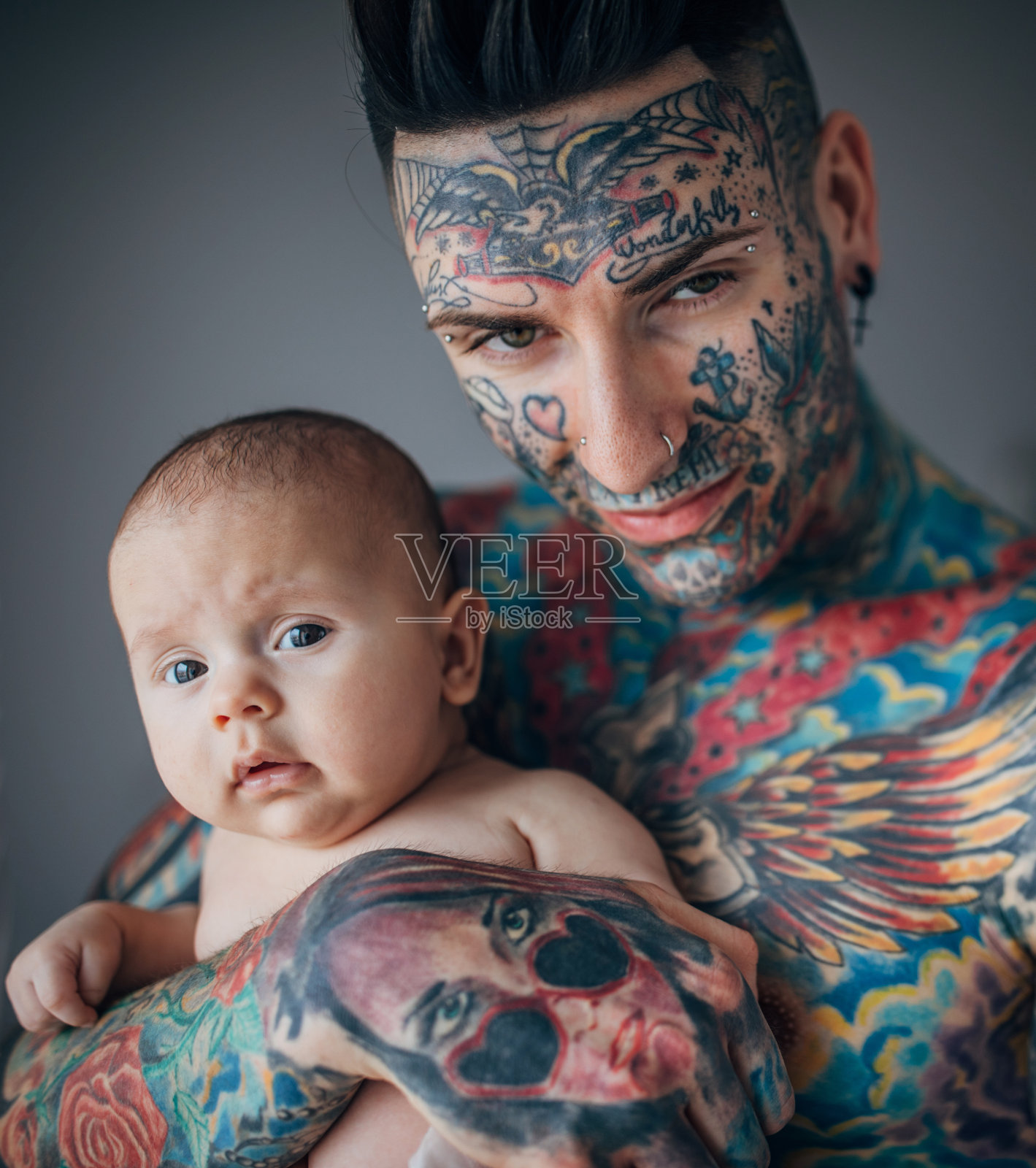 年轻的父亲全身纹身抱着他的儿子照片摄影图片