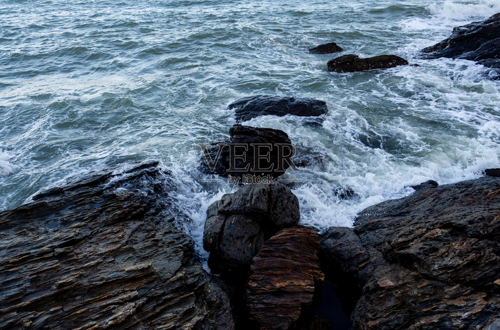 海浪涌向多岩石的海岸。照片摄影图片