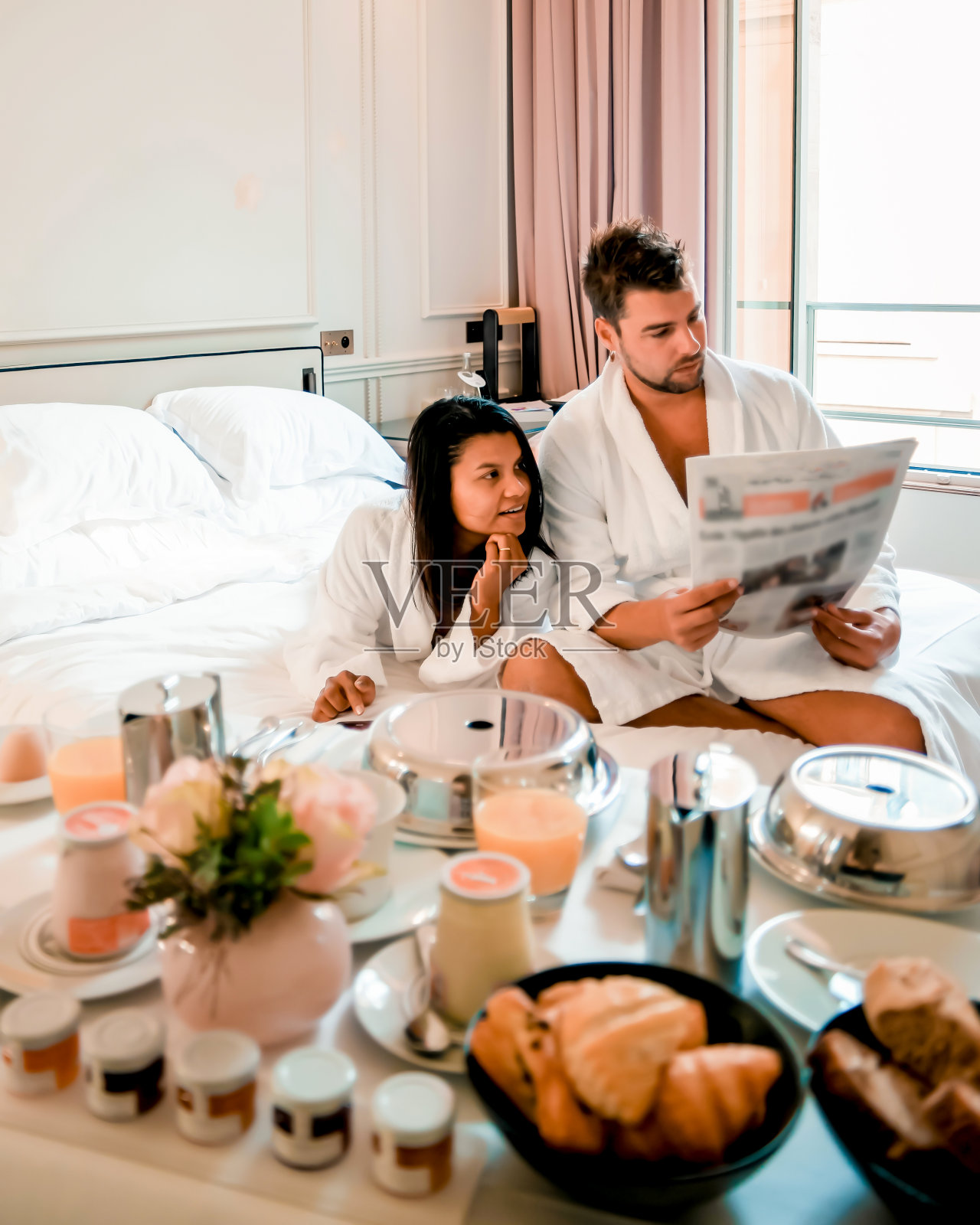 早晨醒来在巴黎的床上，早餐咖啡和报纸，夫妇在床上的男人和女人蜜月情人夫妇照片摄影图片