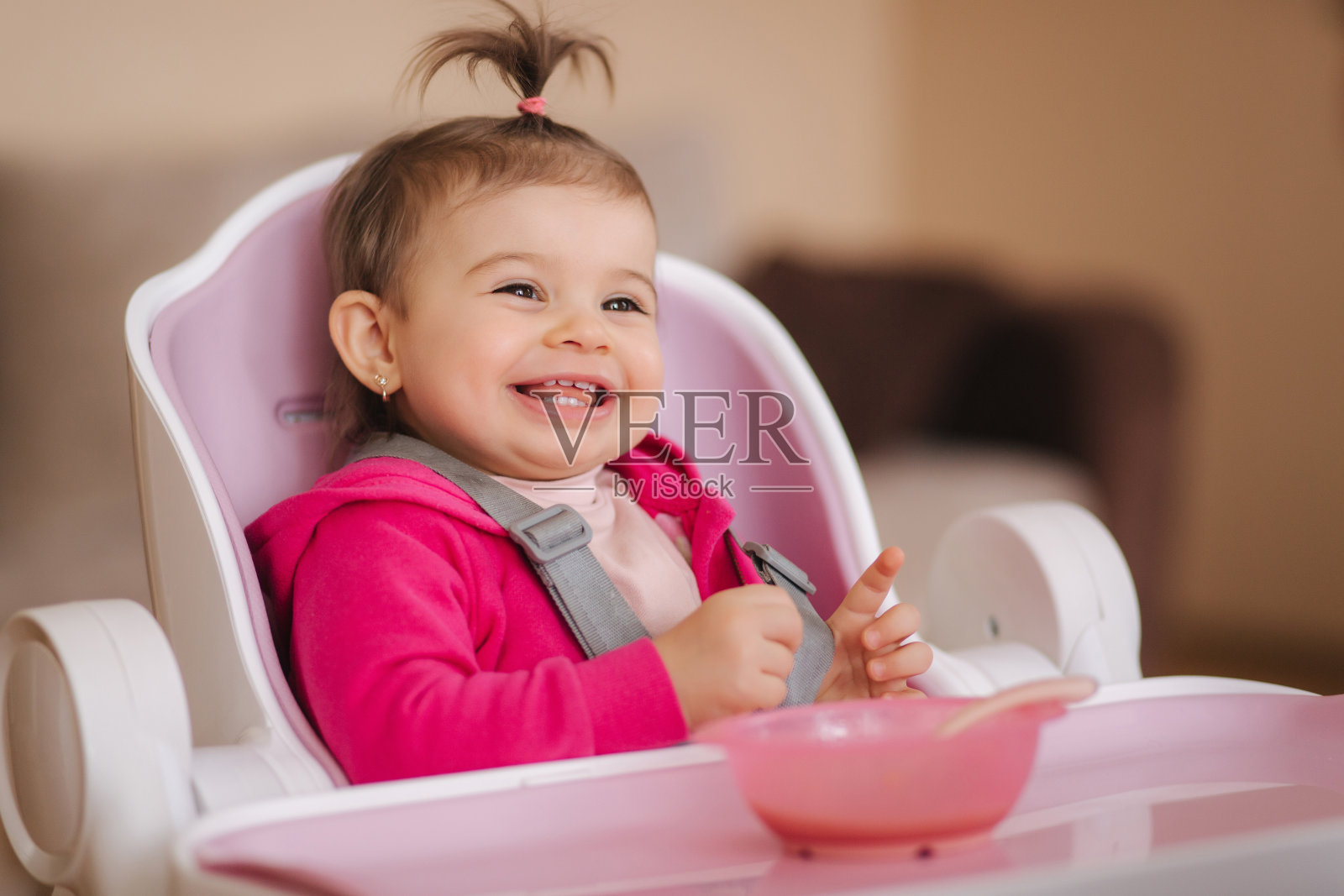 可爱的小女孩正在高椅上吃东西。家里微笑的小孩儿的肖像照片摄影图片