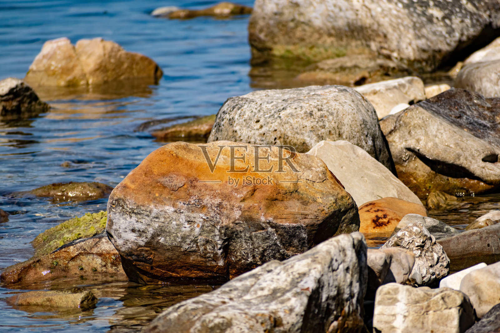 巨大而光滑的石头在咸海水的海岸波浪中。黑海海岸泛着泡沫，咆哮着照片摄影图片