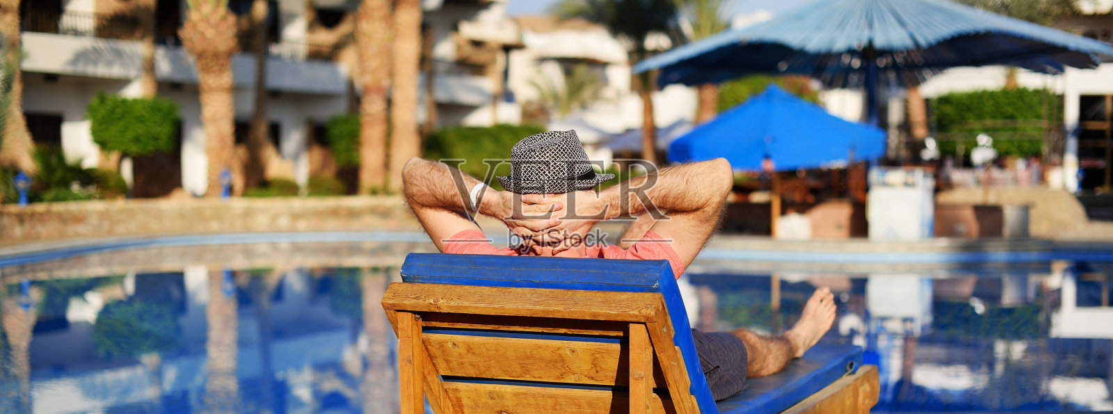 在夕阳的背景下，一个成功的年轻人躺在酒店的躺椅上。全景横幅景观标题。在夏日泳池中放松。旅行的概念时间照片摄影图片