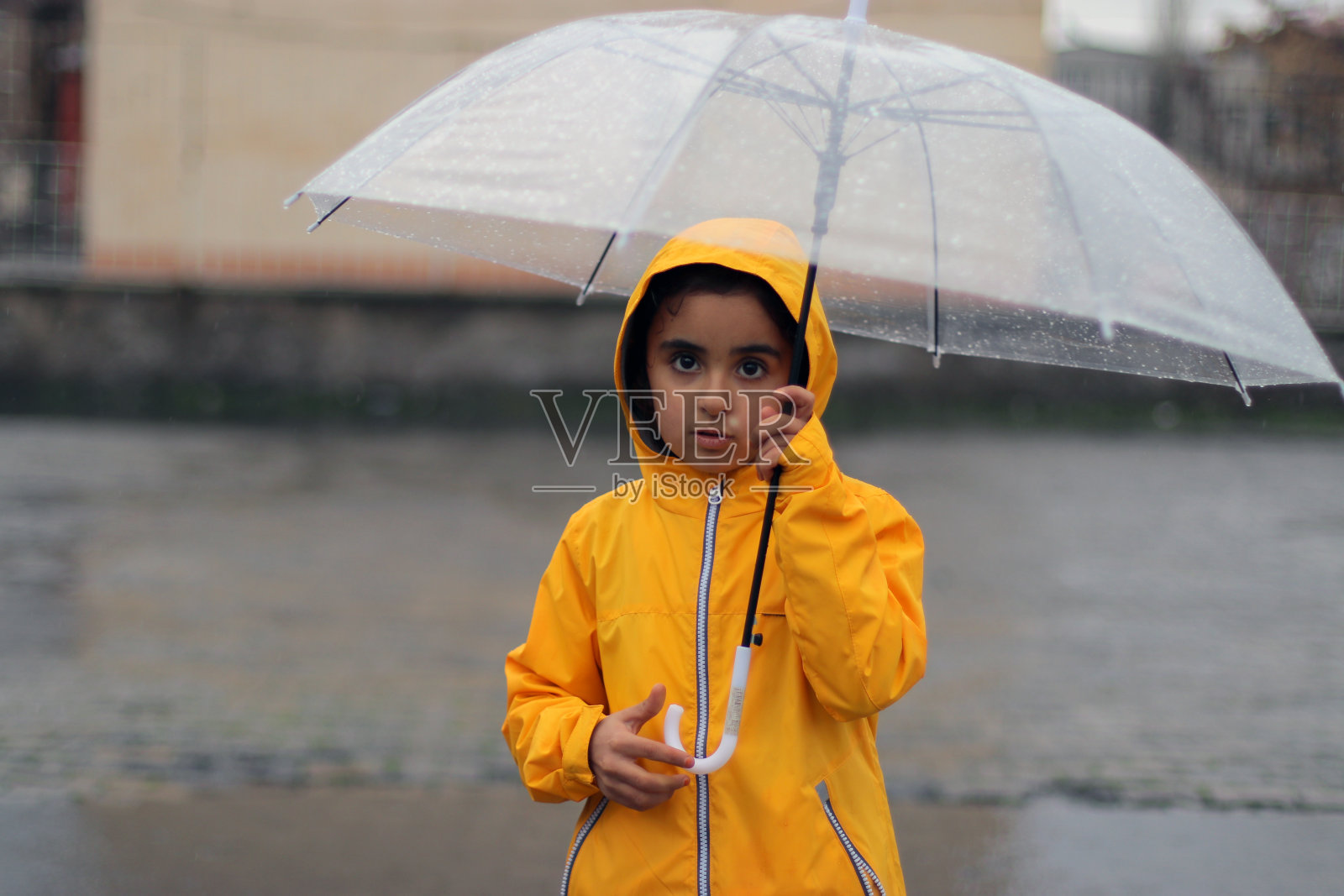 小女孩撑着雨伞在雨中照片摄影图片