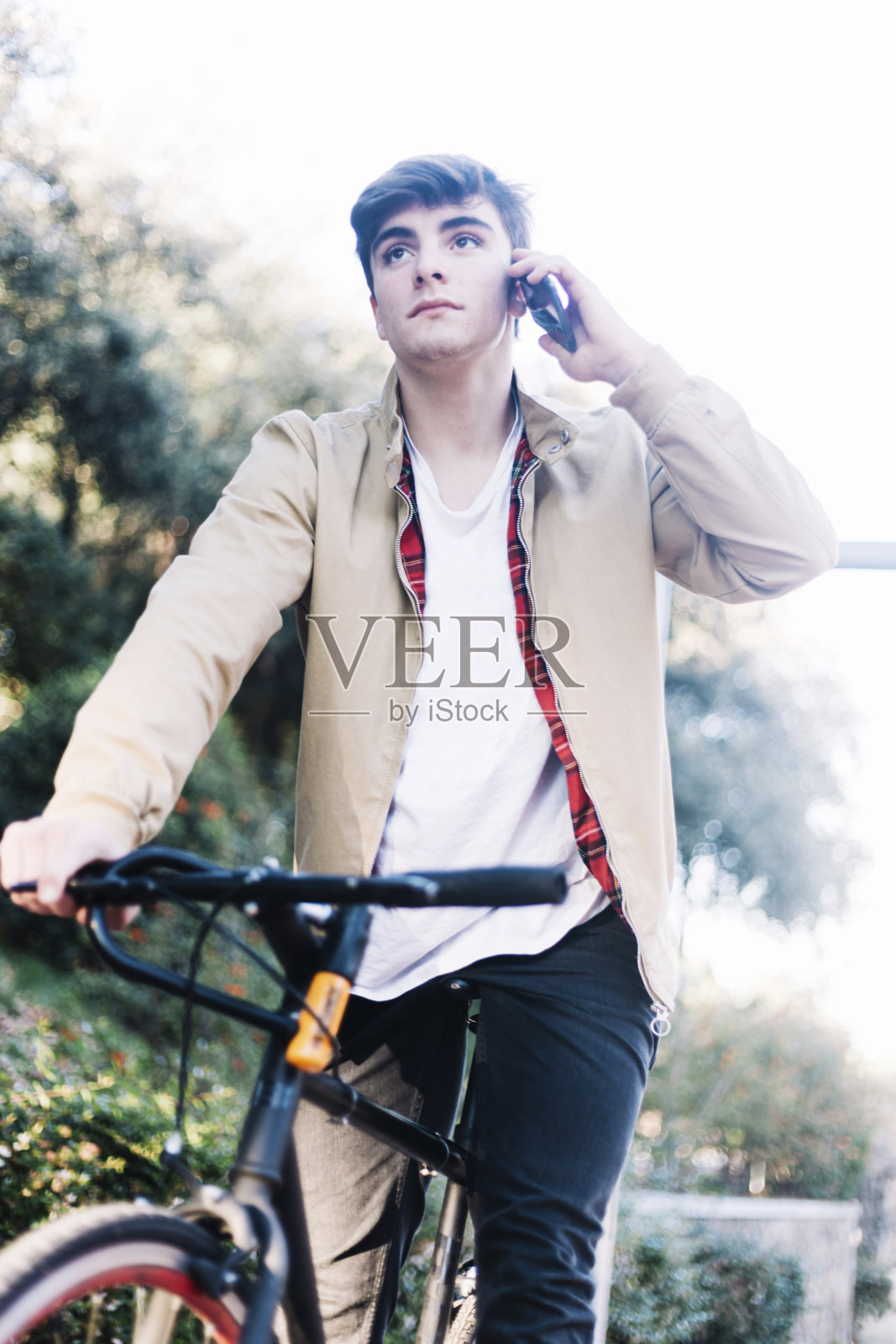 年轻人骑着自行车用手机打电话照片摄影图片