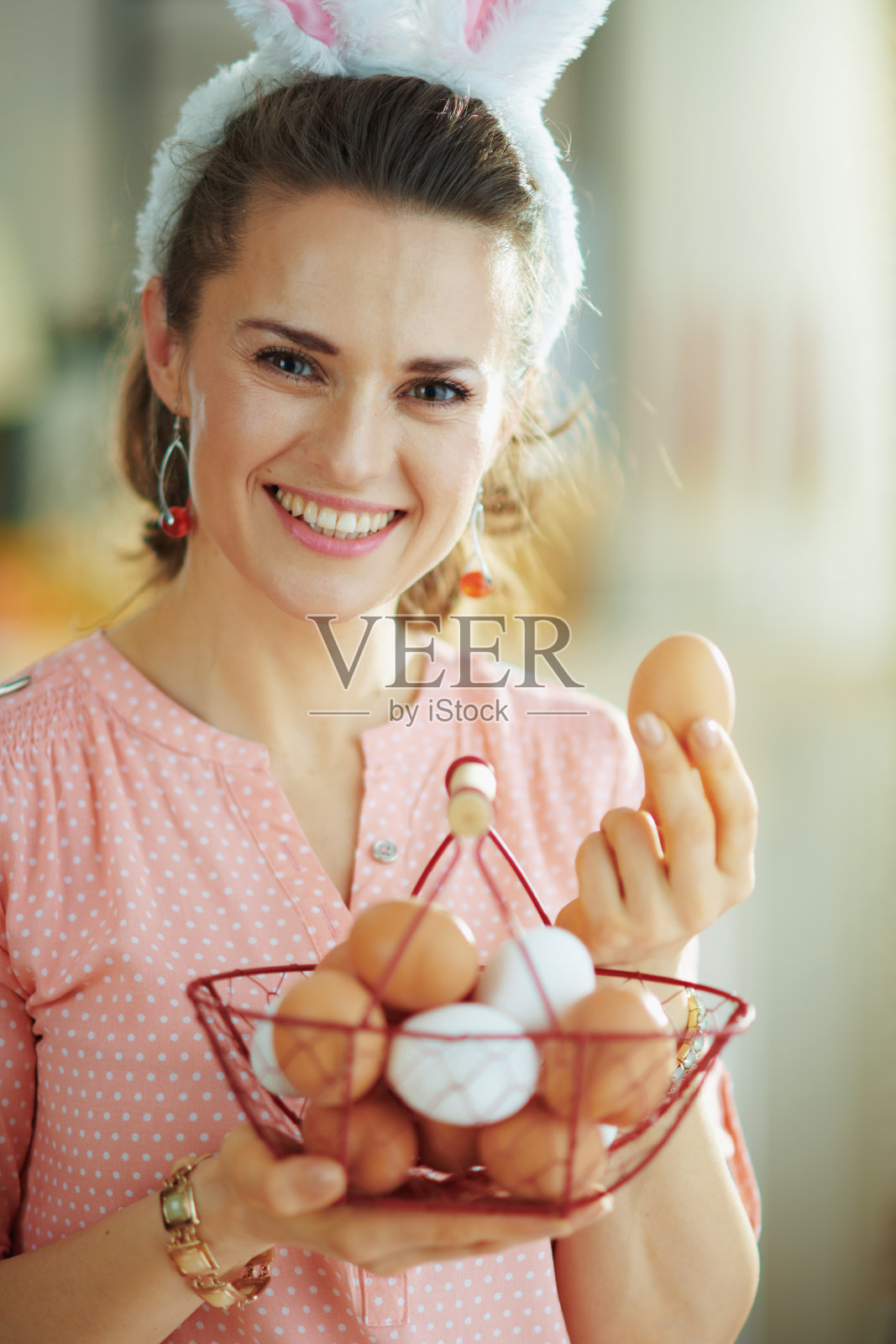 微笑的现代女性抱着篮子与鸡蛋和显示鸡蛋照片摄影图片