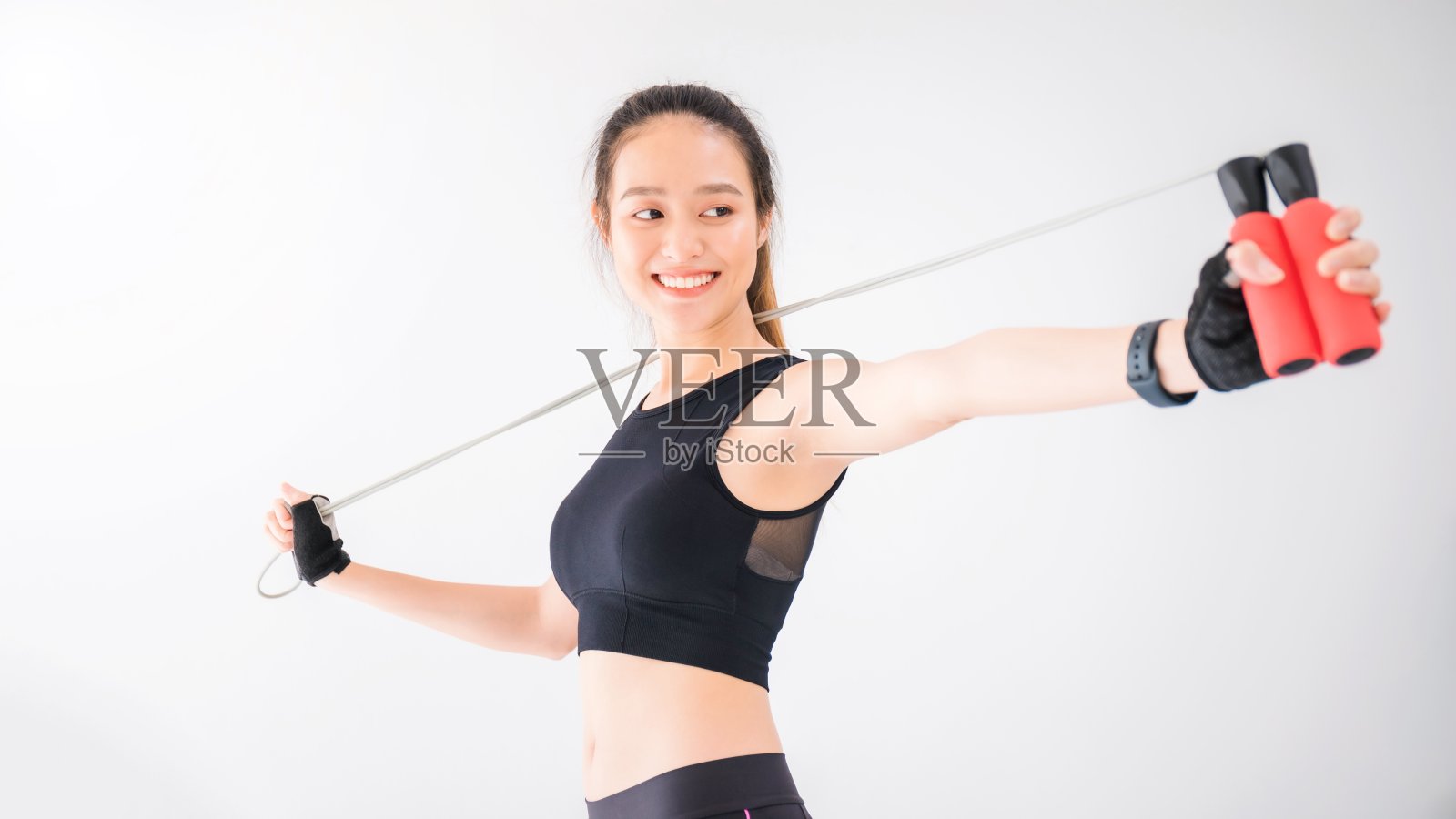 亚洲美丽微笑的妇女运动与跳绳在白色墙壁健身背景。运动可以减肥，增加灵活性，收紧体型。健康的生活方式的概念。照片摄影图片