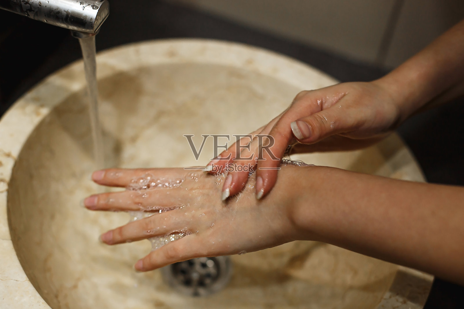 妇女在公共场所的浴室用肥皂洗手。小心洗手，防止致病性病毒和细菌照片摄影图片