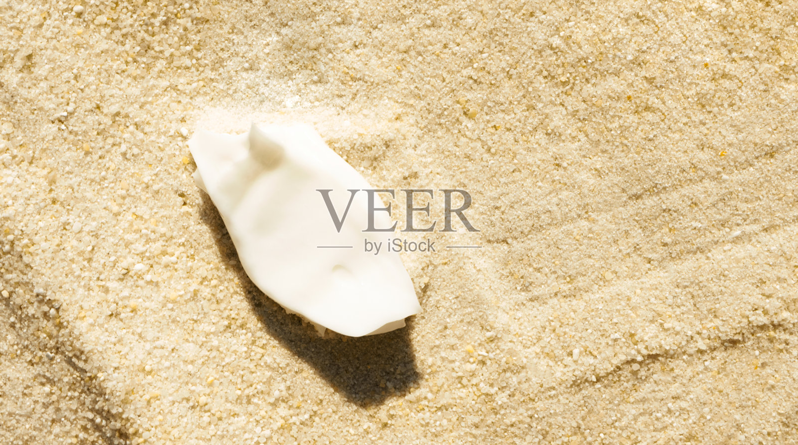 涂抹防晒霜在沙子背景与复制空间。夏季护肤。涂抹保湿乳液，以上照片摄影图片