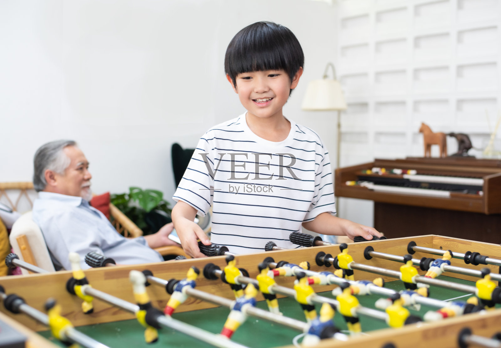 快乐幼小的亚洲孩子在爷爷的背景下在家踢足球，快乐的家庭周末一起在家里休闲。照片摄影图片