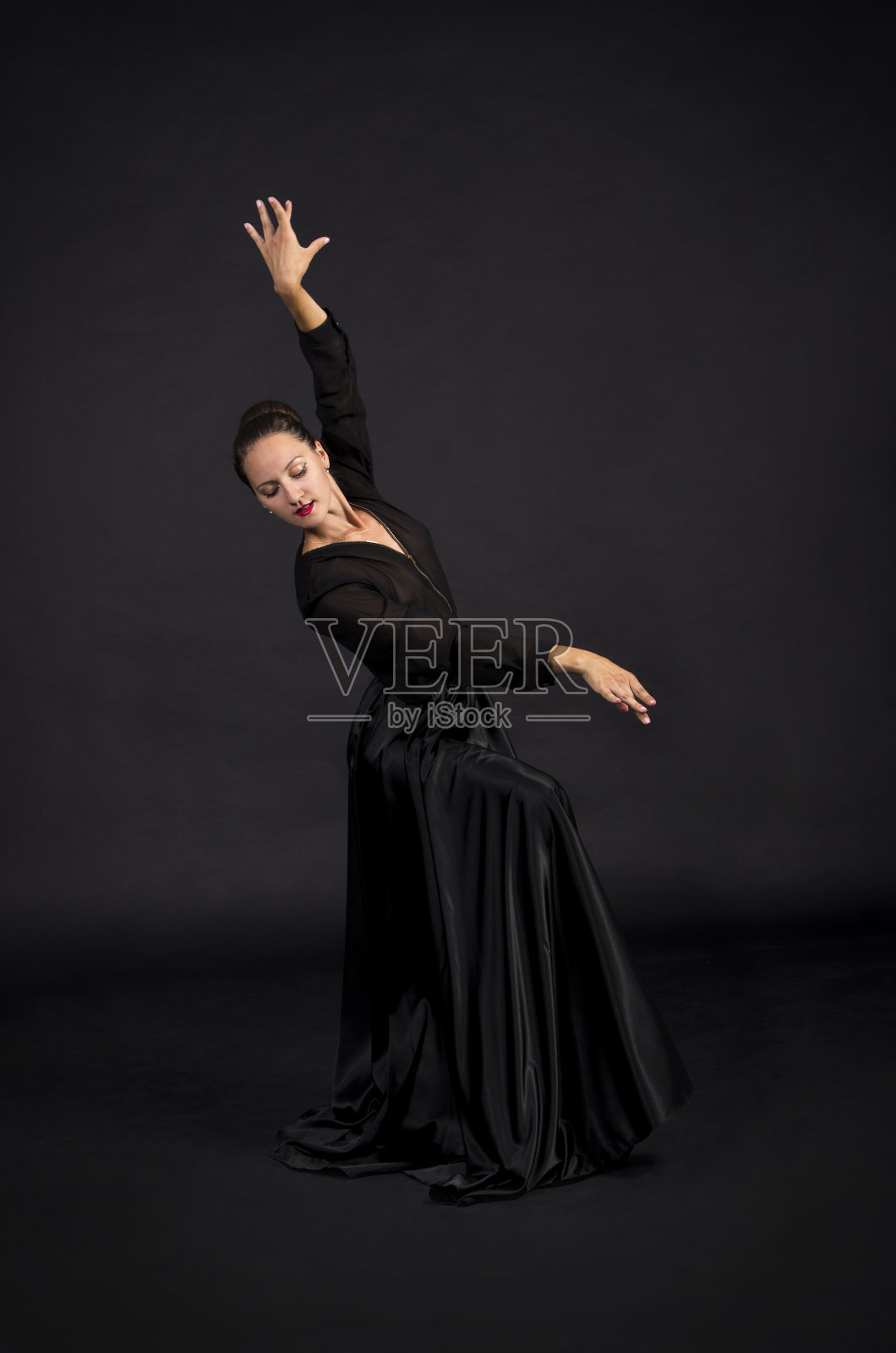 一个年轻的，微笑的女孩在黑色套装跳舞现代编舞。照片摄影图片